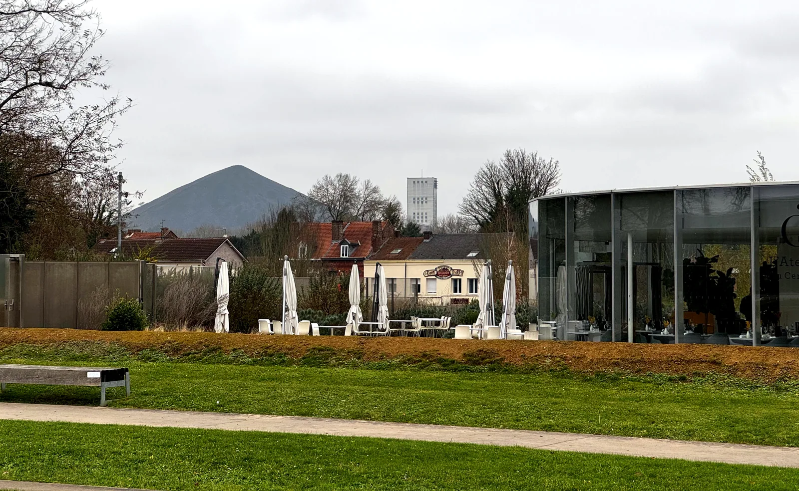Depuis le parc du Louvre-Lens, un terril du 11/19 et la tour du puits 19 au-dessus des maisons de la cité