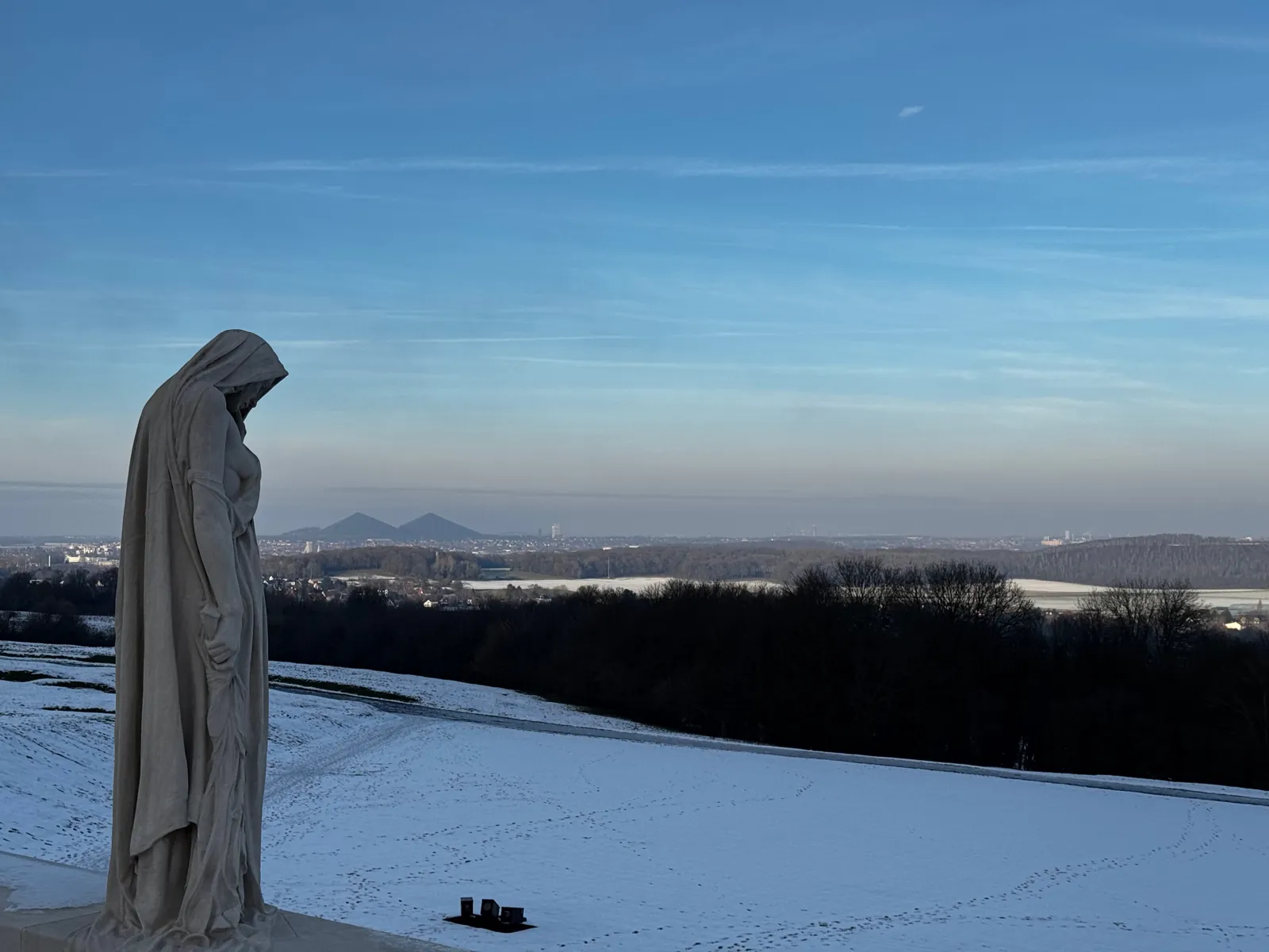 La statue Canada en deuil au mémorial de Vimy, sous la neige, face à la plaine de Lens et aux terrils jumeaux